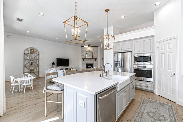 kitchen featuring an inviting chandelier, a sink, light wood-style flooring, appliances with stainless steel finishes, and open floor plan