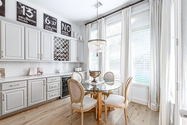 dining area with wine cooler, visible vents, a bar, and light wood-style flooring