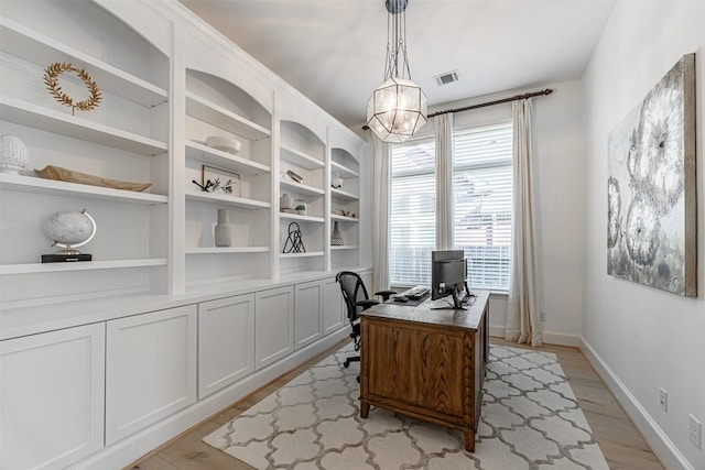office area featuring baseboards, light wood-style flooring, visible vents, and an inviting chandelier