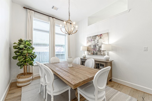 dining space featuring light wood-type flooring, baseboards, a notable chandelier, and visible vents