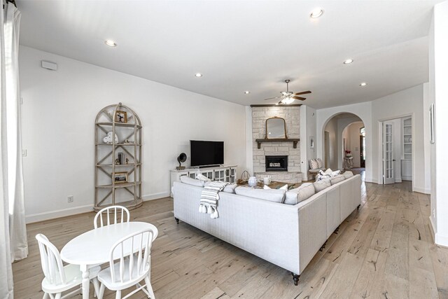 living area with arched walkways, a ceiling fan, light wood-style floors, and recessed lighting