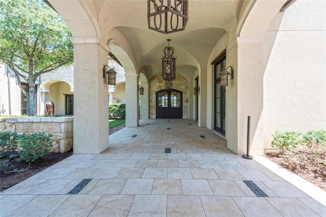 entrance to property featuring stucco siding, stone siding, and french doors