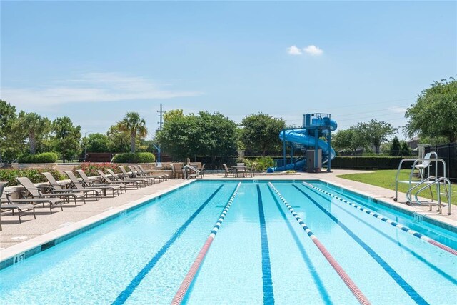 community pool with fence, a water slide, and a patio