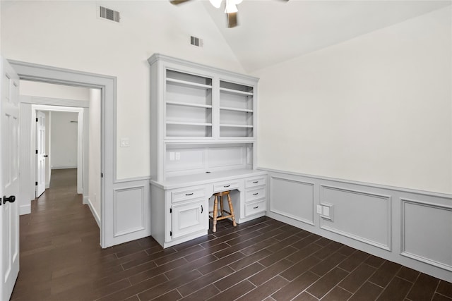 unfurnished office with built in desk, visible vents, ceiling fan, and a decorative wall