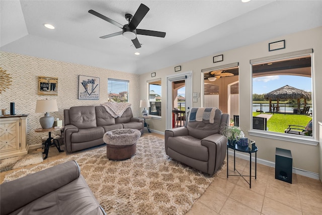 living area with baseboards, wallpapered walls, tile patterned flooring, ceiling fan, and a water view