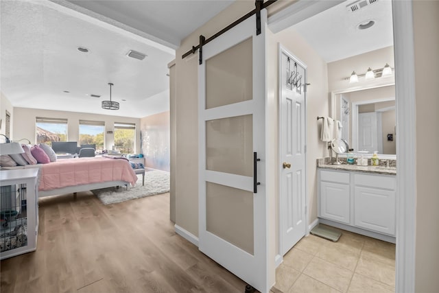 interior space featuring light wood-type flooring, visible vents, and a barn door