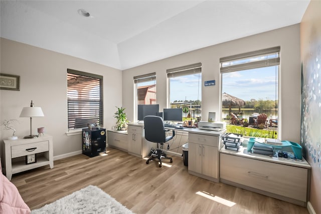 office space featuring light wood-style flooring, baseboards, and vaulted ceiling