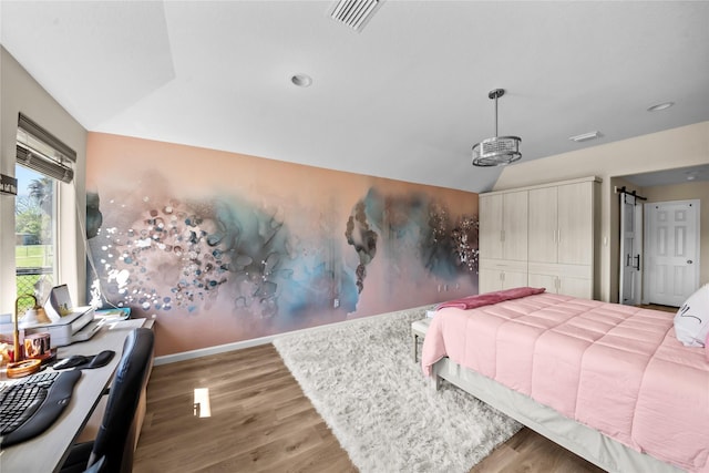 bedroom featuring visible vents, baseboards, wood finished floors, and vaulted ceiling