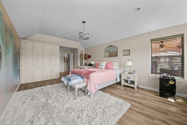 bedroom with visible vents, baseboards, wood finished floors, and lofted ceiling