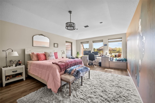 bedroom with access to exterior, a tray ceiling, light wood-style flooring, and visible vents
