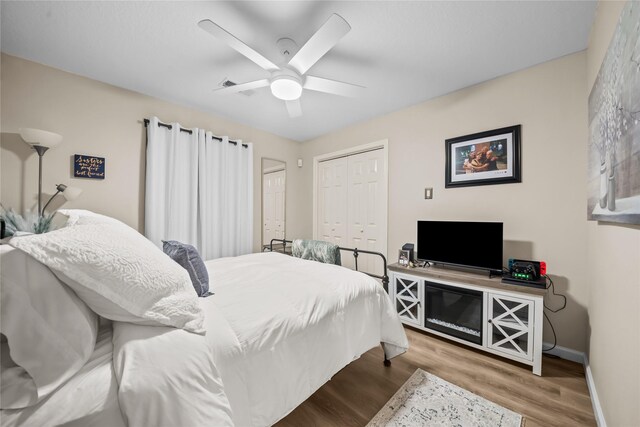 bedroom with a closet, baseboards, ceiling fan, and wood finished floors