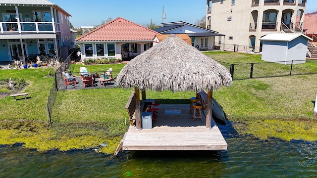 view of dock featuring a water view, a fenced backyard, and a lawn