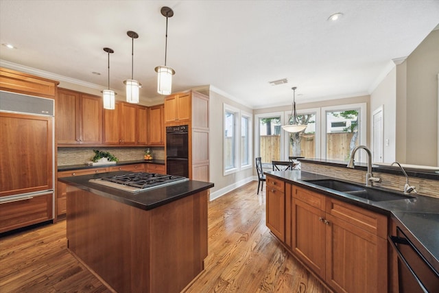 4404 Wendell St, Bellaire, TX 77401 - kitchen featuring paneled built in fridge, a sink, stainless steel gas stovetop, dark countertops, and crown molding