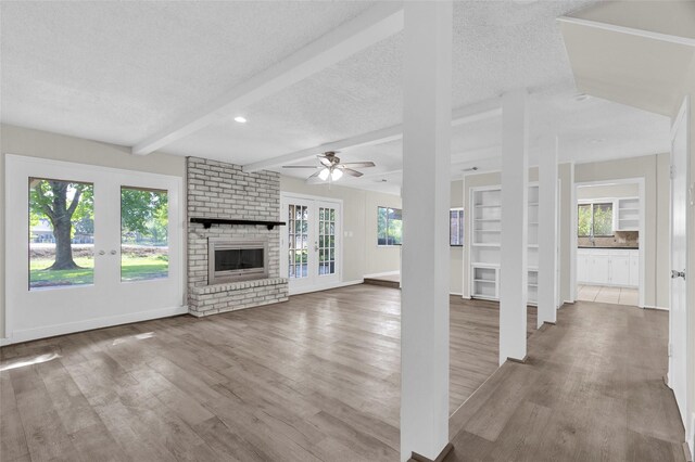 3142 La Quinta Dr, Missouri City, TX 77459 - unfurnished living room featuring a brick fireplace, wood finished floors, and plenty of natural light