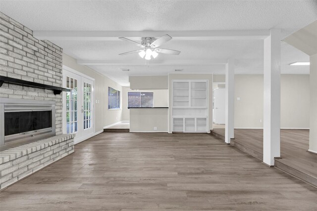 3142 La Quinta Dr, Missouri City, TX 77459 - unfurnished living room with a brick fireplace, wood finished floors, a ceiling fan, beamed ceiling, and a textured ceiling