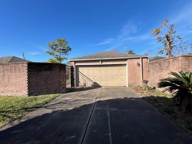 exterior space featuring concrete driveway, roof with shingles, fence, and an attached garage