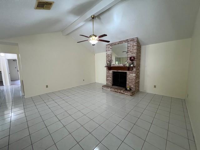 unfurnished living room with visible vents, light tile patterned floors, a brick fireplace, lofted ceiling with beams, and a ceiling fan