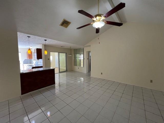 unfurnished living room featuring visible vents, light tile patterned floors, plenty of natural light, a ceiling fan, and vaulted ceiling with beams