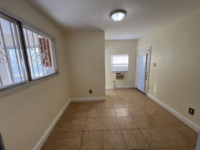 tiled empty room featuring baseboards