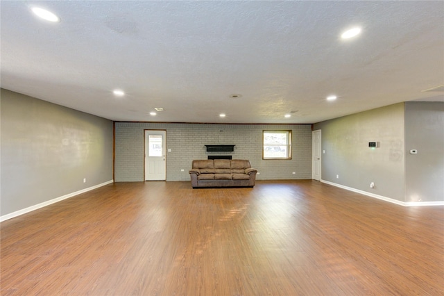 811 Strange Dr, Richmond, TX 77406 - unfurnished living room featuring wood finished floors, baseboards, a brick fireplace, and recessed lighting