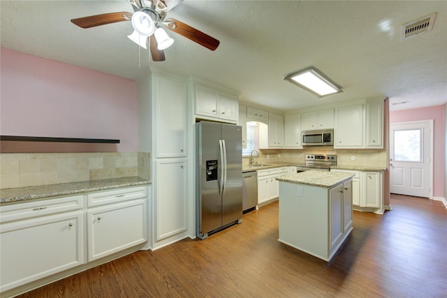 811 Strange Dr, Richmond, TX 77406 - kitchen with tasteful backsplash, white cabinets, visible vents, wood finished floors, and stainless steel appliances