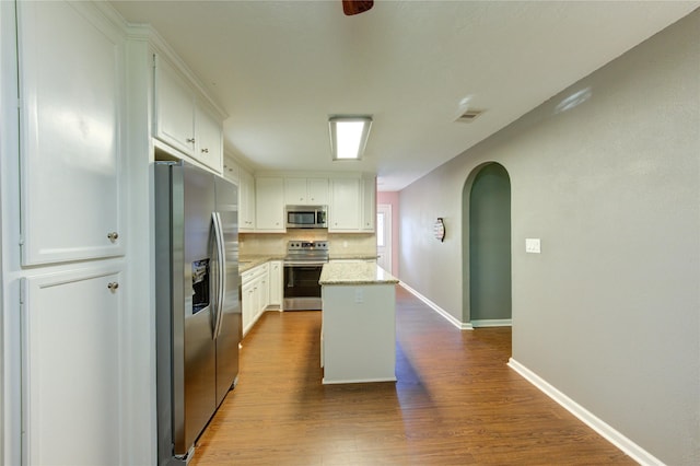 811 Strange Dr, Richmond, TX 77406 - kitchen featuring a kitchen island, dark wood-type flooring, visible vents, appliances with stainless steel finishes, and arched walkways