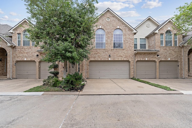 multi unit property featuring a garage, driveway, and brick siding