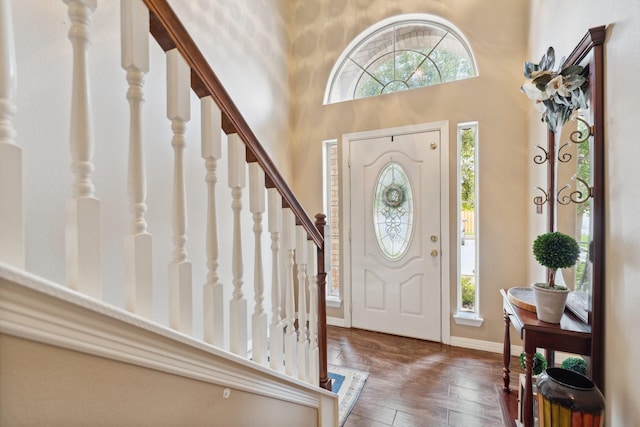 foyer featuring stairs, a towering ceiling, baseboards, and wood finished floors