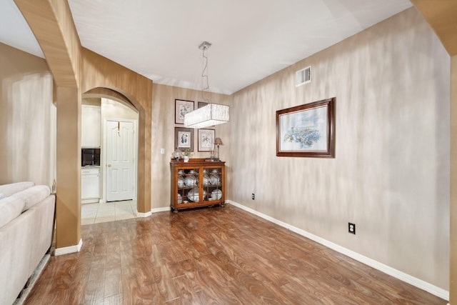 dining area featuring arched walkways, visible vents, baseboards, and wood finished floors
