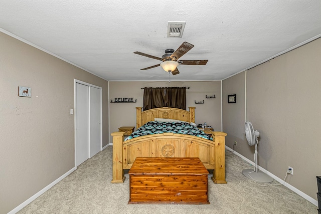bedroom featuring visible vents, ceiling fan, a textured ceiling, crown molding, and light carpet