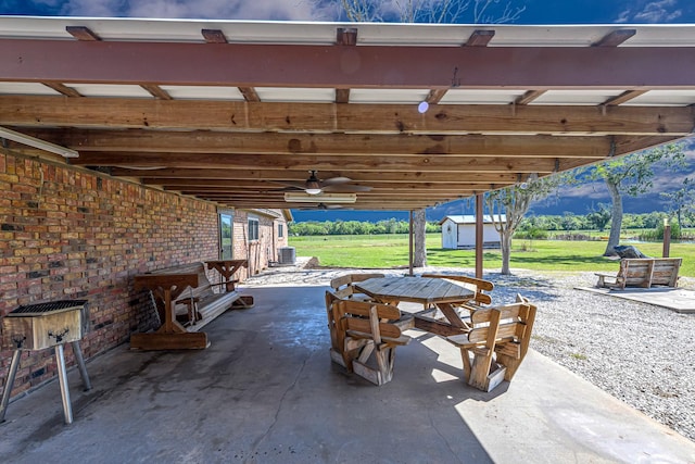 view of patio featuring central AC unit, a ceiling fan, an outdoor structure, outdoor dining area, and a storage unit