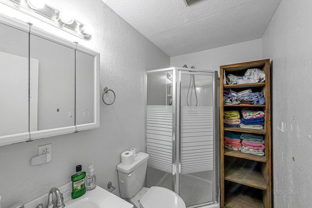 full bath with a shower stall, a textured ceiling, a sink, and toilet