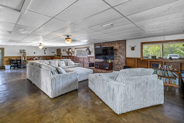 living area featuring a drop ceiling, concrete floors, wainscoting, and visible vents