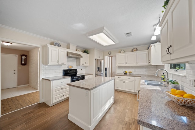 kitchen with tasteful backsplash, stainless steel refrigerator with ice dispenser, exhaust hood, a sink, and black range with electric stovetop