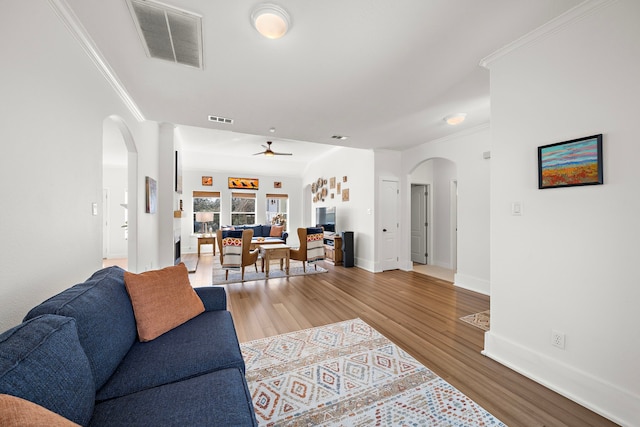 living room featuring arched walkways, wood finished floors, a ceiling fan, and visible vents