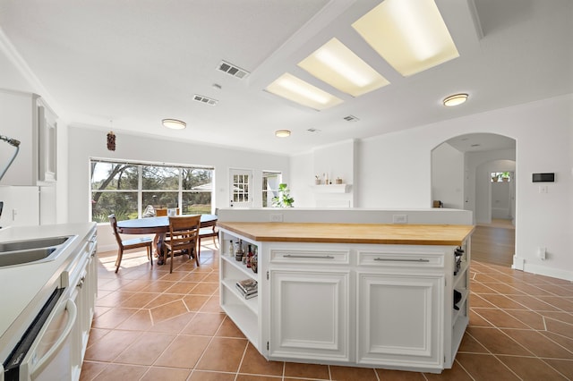kitchen with visible vents, open shelves, white dishwasher, wood counters, and tile patterned flooring