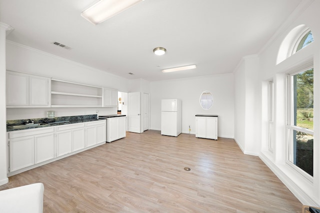 kitchen with crown molding, freestanding refrigerator, open shelves, dark countertops, and visible vents
