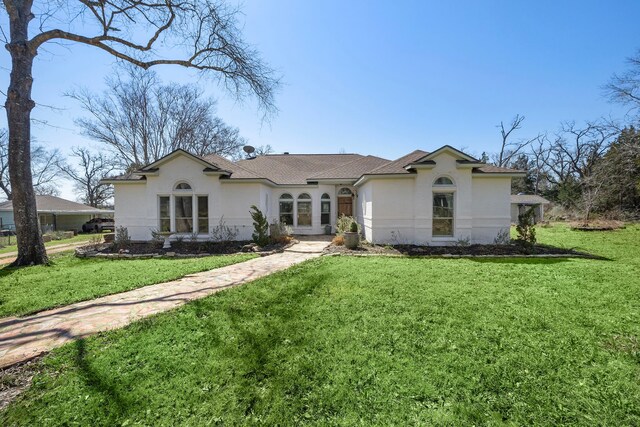 view of front of house with a front yard, roof with shingles, and stucco siding