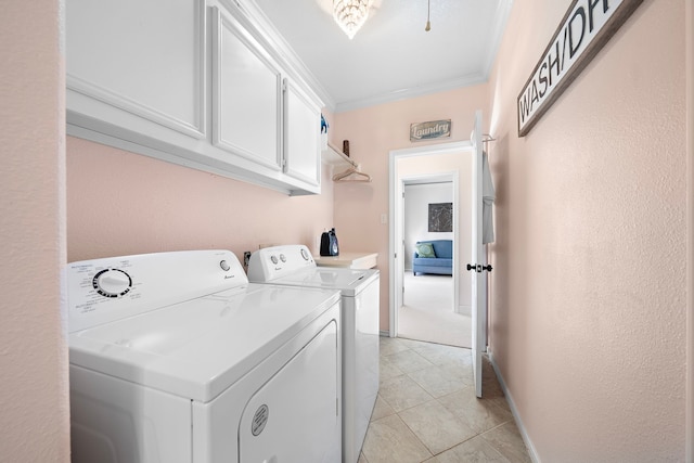 laundry room with crown molding, washing machine and clothes dryer, cabinet space, and light tile patterned floors