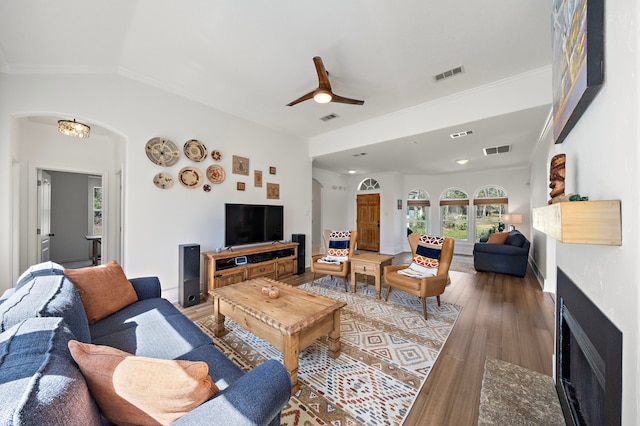 living room with light wood-style flooring, arched walkways, and visible vents