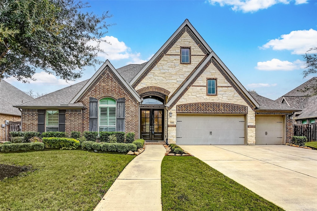 30406 Wild Garden Way Ct, Fulshear, TX 77441 - french provincial home featuring a front yard, stone siding, brick siding, french doors, and concrete driveway