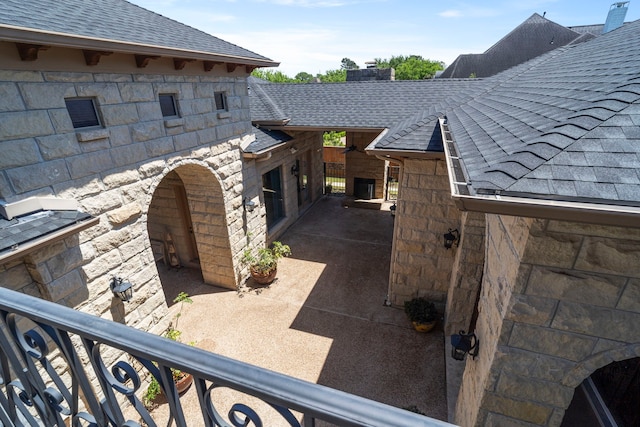 view of home's exterior with roof with shingles and stone siding