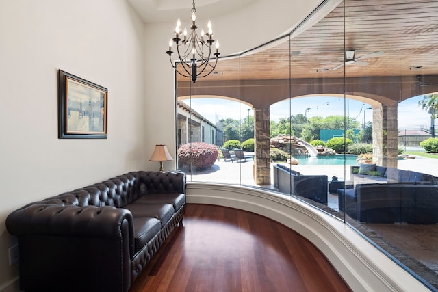 living area featuring ceiling fan with notable chandelier and wood finished floors
