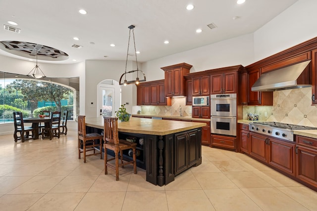 kitchen with visible vents, appliances with stainless steel finishes, wall chimney exhaust hood, and light tile patterned floors