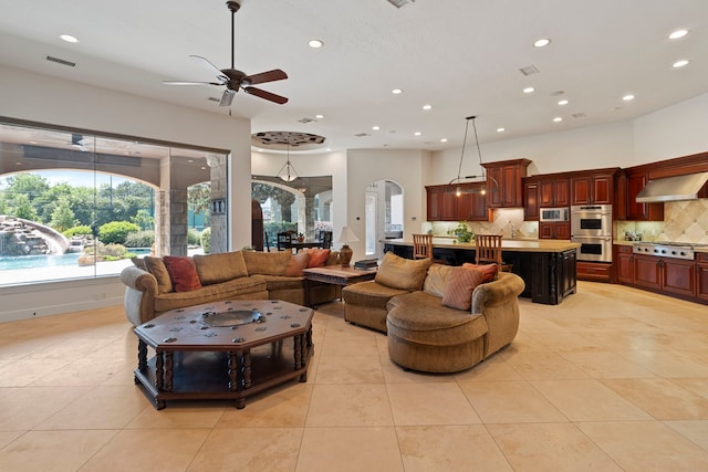 living area with arched walkways, light tile patterned floors, a ceiling fan, and recessed lighting