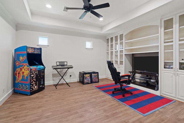 home office featuring a raised ceiling, wood finished floors, ceiling fan, and baseboards