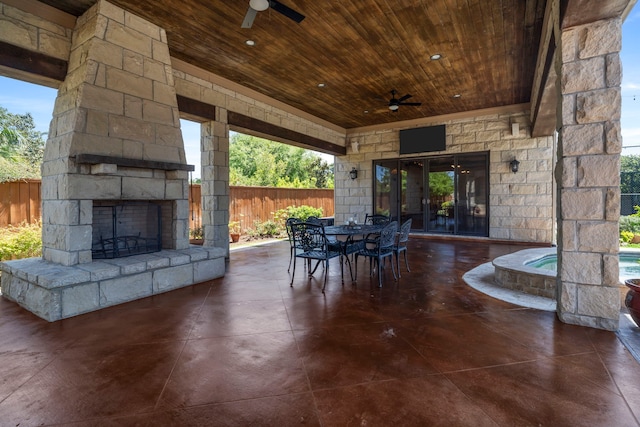 view of patio / terrace featuring outdoor dining space, fence, an outdoor stone fireplace, and ceiling fan