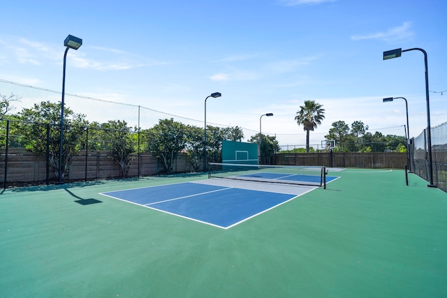 view of tennis court with community basketball court and fence