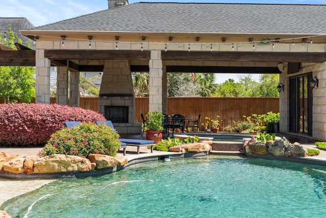 outdoor pool with a gazebo, a patio area, fence, and an outdoor stone fireplace