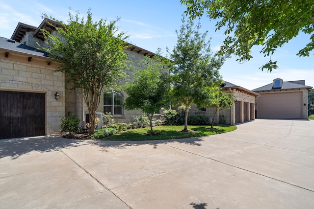 view of front of property with central AC unit, driveway, a garage, and stone siding